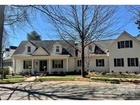 Charming white home with black shutters, a covered porch, and manicured landscaping at 357 Magnolia St, Davidson, NC 28036