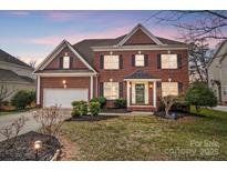 Charming two-story brick home featuring a well-manicured lawn, attached garage and traditional architectural details at 561 Ambergate Nw Pl, Concord, NC 28027