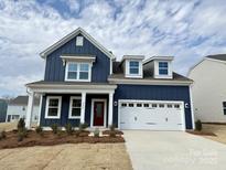 Charming two-story home with blue siding, white trim, a red front door and an attached two car garage at 8224 Annsborough Nw Dr, Concord, NC 28027