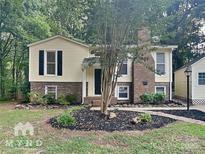 Charming split-level home with yellow siding, brick accents, and mature trees in a landscaped yard at 3029 Winding Trl, Matthews, NC 28105