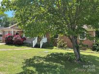 Charming brick home with a well-manicured lawn, mature tree, and inviting front porch at 784 Crestmont Se Dr, Concord, NC 28025