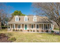 Inviting home featuring a cozy front porch, dormer windows, and a well-maintained lawn at 12325 Parks Farm Ln, Charlotte, NC 28277