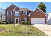 Charming brick two-story home with manicured lawn and attached two car garage in a suburban neighborhood at 12907 Mccahan Ln, Huntersville, NC 28078