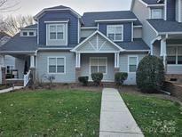 Two-story townhome boasts a charming exterior, featuring gray siding and a welcoming front porch at 14955 Alexander Place Dr, Huntersville, NC 28078