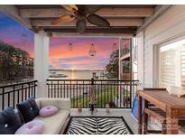 Relaxing balcony features lake view, ceiling fan, outdoor furniture, and stylish zebra rug on beautiful sunset at 17811 Half Moon Ln # E, Cornelius, NC 28031