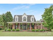Charming brick home with a wide, covered porch and manicured landscaping, creating a welcoming curb appeal at 3300 Chancellor Ln, Monroe, NC 28110