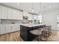 Modern kitchen with white cabinets, gray backsplash, and a large center island at 4122 Eastover Glen Rd # 0316, Charlotte, NC 28269