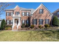 Brick two-story house with black shutters, white columns, and a manicured lawn at 8809 Landsdowne Ave, Harrisburg, NC 28075