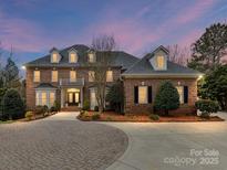 Elegant brick home featuring manicured landscaping, a circular driveway, and classic architectural details at 14407 Brick Church Ct, Charlotte, NC 28277