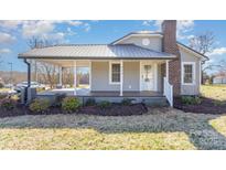 Charming home with inviting front porch, gray siding, metal roof, and well-maintained landscaping at 214 E Main St, Cleveland, NC 27013