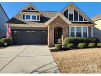 Charming home with a stone facade entrance, black garage door, manicured lawn, and an American flag at 4929 Norman Park Pl, Lake Wylie, SC 29710