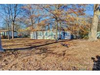 Mobile home exterior with tree-lined yard and shed at 6415 Sherwood Ln, Denver, NC 28037