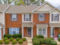 Attractive brick townhome featuring multi-pane windows, a covered entryway, and manicured shrubs at 8065 Stoneham Ct, Matthews, NC 28105