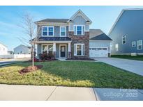 Charming two-story home featuring stone accents, a well-manicured lawn, and a welcoming front entrance at 10103 Andres Duany Dr, Huntersville, NC 28078