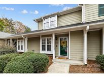 Charming two-story home features a covered entryway, lush landscaping, and a welcoming green front door at 2745 Tiergarten Ln, Charlotte, NC 28210