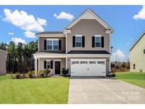 Two-story house with a beige exterior, white garage door, and landscaped lawn at 6351 Trinity Crossing Cir, Kannapolis, NC 28081
