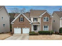 Charming brick two-story home featuring an attached two-car garage and manicured front lawn at 14104 Green Birch Dr, Pineville, NC 28134