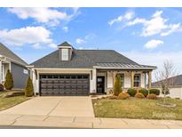 Charming single-story home with a dark gray garage door, covered porch with wooden pillars, and manicured lawn at 473 Bowline Dr, Denver, NC 28037