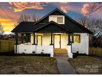Charming home with a welcoming front porch, painted brick facade, and beautiful landscaping at sunset at 49 8Th Se St, Hickory, NC 28602