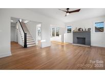 Bright living room featuring hardwood floors, brick fireplace, and staircase at 49 8Th Se St, Hickory, NC 28602