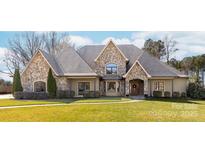 Stone-accented home showcasing a well-manicured lawn, mature trees, and a welcoming facade at 148 Castle Dr, Mooresville, NC 28117