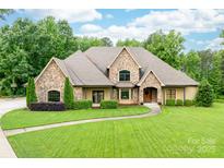 Charming stone-accented home featuring a meticulously manicured lawn and mature landscaping at 148 Castle Dr, Mooresville, NC 28117