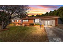 Charming brick home with a well-manicured lawn, colorful landscaping, and attached two-car garage under a beautiful sunset sky at 7320 Old Mocksville Rd, Salisbury, NC 28144