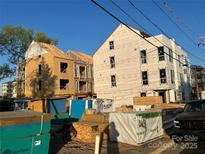 New construction site featuring modern architecture with visible framing and wrapped exteriors, showcasing ongoing development at 115 Verbena Ne St # 12, Charlotte, NC 28217