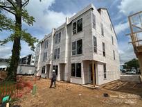 New three-story home with large windows and durable protective wrap under construction at 115 Verbena Ne St # 12, Charlotte, NC 28217
