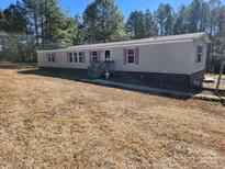 Tan single-wide mobile home with pink shutters and a stone base at 26174 Treece Rd, Albemarle, NC 28001