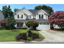 Charming two-story home featuring a well-manicured lawn, flowering trees, and a welcoming front porch at 5934 Hickory Hollow Ct, Harrisburg, NC 28075
