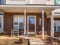 Inviting brick front exterior with rocking chair and covered porch at 7677 Petrea Ln, Charlotte, NC 28227