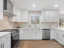 Modern kitchen with white cabinets, stainless steel appliances, tile backsplash, and hardwood floors at 122 Lansdowne Rd, Charlotte, NC 28270