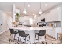 A spacious kitchen features an island with bar seating, white cabinets, and modern lighting fixtures at 124 Doncaster Dr, Mooresville, NC 28115