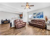 Open living room with hardwood floors, ceiling fan, and comfortable leather couches and decor at 425 Webb Rd, Shelby, NC 28152