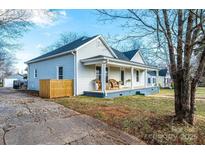 Charming home featuring a welcoming front porch with rocking chairs and mature trees at 909 1St S Ave, Conover, NC 28613