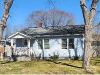 Charming light blue home featuring a welcoming front porch, well-maintained lawn and a beautiful treed front yard at 128 N Oak St, Salisbury, NC 28146