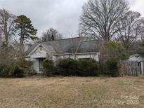 Shows the exterior of a one story home with an overgrown yard and peeling paint at 2801 Pennsylvania Ave, Kannapolis, NC 28083