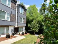 Modern townhouse with a well-manicured lawn and a combination of gray panels and wooden accents on the exterior at 7020 Loso Commons Way, Charlotte, NC 28217