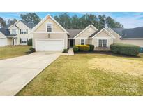 Beige house with a two-car garage and well-maintained lawn at 7021 Merrymount Ct, Concord, NC 28025