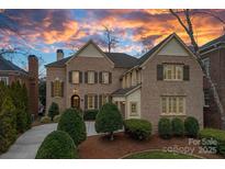 Charming two-story brick home featuring classic shutters, manicured landscaping, and a vibrant sunset backdrop at 8908 Heydon Hall Cir, Charlotte, NC 28210
