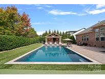 Beautiful backyard featuring a pool, cabana, and manicured landscaping, perfect for outdoor entertaining at 14507 Old Vermillion Dr, Huntersville, NC 28078