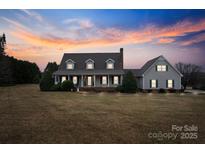 Charming home featuring a welcoming front porch, well-manicured lawn, and a picturesque sunset backdrop at 2370 Old Mountain Rd, Statesville, NC 28625