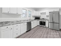 Bright kitchen features stainless appliances, gray counters and backsplash, and white cabinetry at 63 3Rd Nw St, Concord, NC 28027