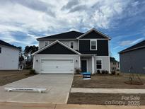Two-story home featuring a two-car garage, a dark gray accent wall, and a well-manicured lawn at 1517 Harper Landing Blvd, Stanley, NC 28164