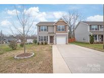 Charming two-story home with a well-manicured lawn and a long driveway leading to an attached garage at 610 John St, Monroe, NC 28110