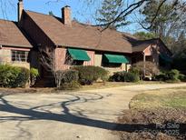 Charming single-story brick home with beautiful landscaping, driveway, and green awnings offers comfort and style at 1124 Evergreen Cir, Rock Hill, SC 29732