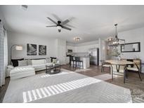 Bright, open-concept living area with modern furnishings, ceiling fan and eat-in kitchen in a neutrally decorated home at 116 Briana Marie Way, Indian Trail, NC 28079