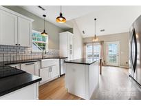 Bright kitchen with white cabinets, black countertops, stainless steel appliances, and hardwood floors at 1836 Danny Ct, Matthews, NC 28105