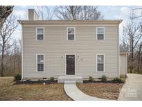 Two-story home featuring neutral siding, a dark front door, and a simple walkway leading to the entrance at 8137 Sheringham Way, Charlotte, NC 28227
